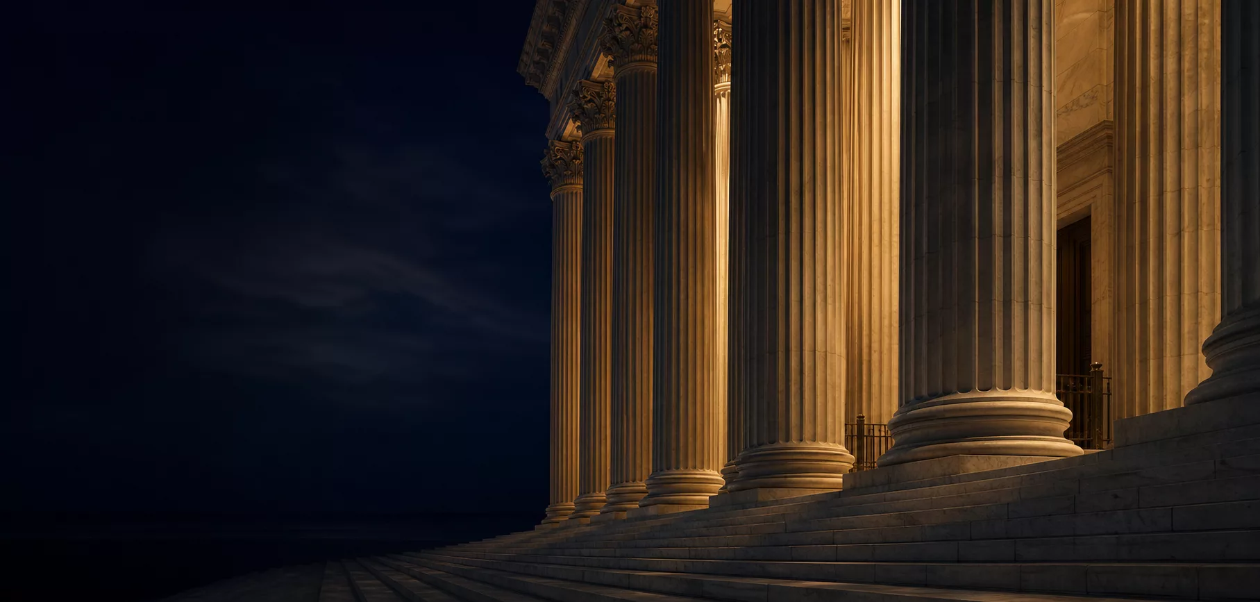 Classical courthouse columns lit warmly against a dark evening sky